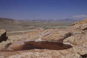 Scenic view of Big Skunk Granite Rock Pool 1989-06-08, #0222, with Independence Rock in distance; has fairy shrimp; Pathfinder National Wildlife Refuge